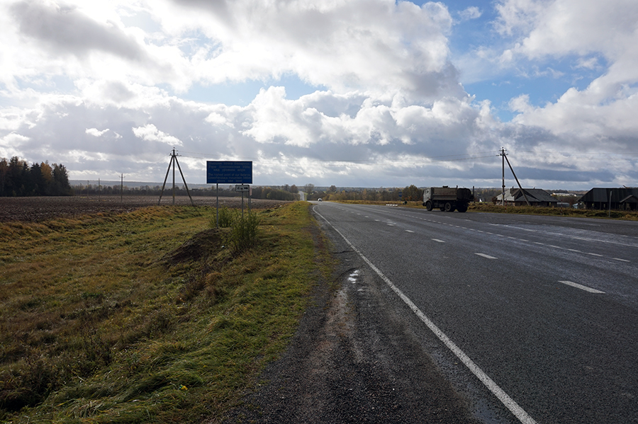 widok drogi od strony wsi Wiertniki, po lewej stronie tablica informująca o szczycie